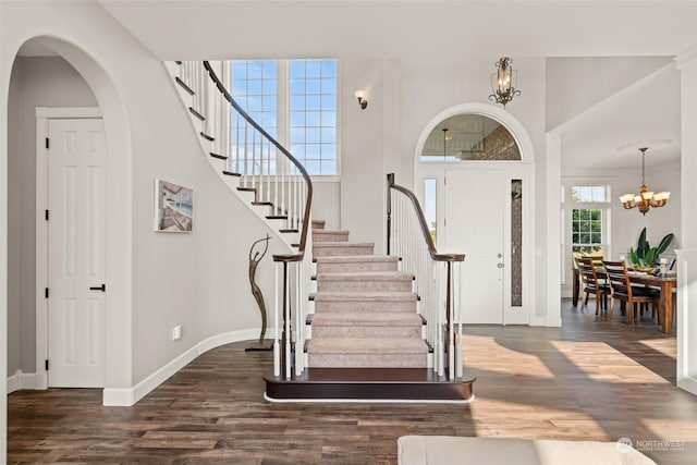 foyer with dark hardwood / wood-style floors, a notable chandelier, and a towering ceiling