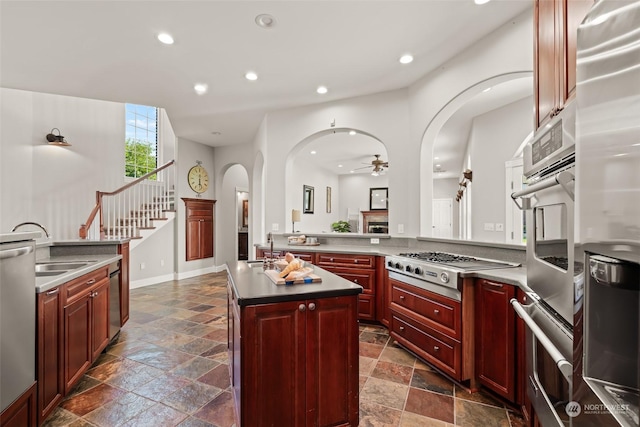 kitchen featuring appliances with stainless steel finishes, ceiling fan, a kitchen island, sink, and kitchen peninsula