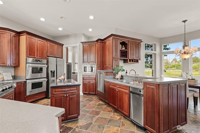 kitchen with sink, an island with sink, hanging light fixtures, and stainless steel appliances