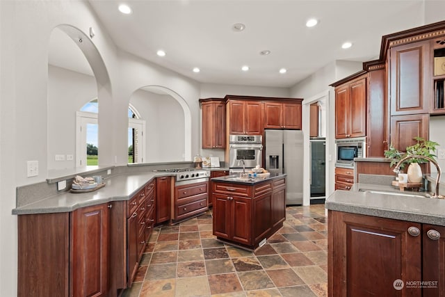 kitchen with sink, kitchen peninsula, a kitchen island, and stainless steel appliances