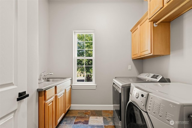 laundry area featuring cabinets, washer and dryer, and sink