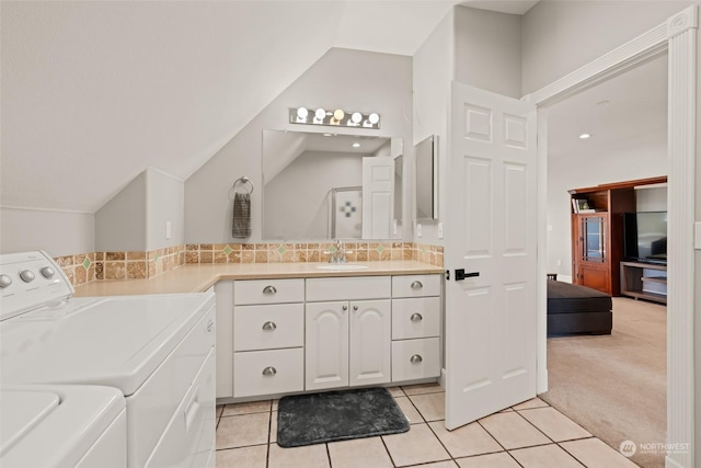 bathroom with lofted ceiling, tile patterned flooring, backsplash, vanity, and separate washer and dryer