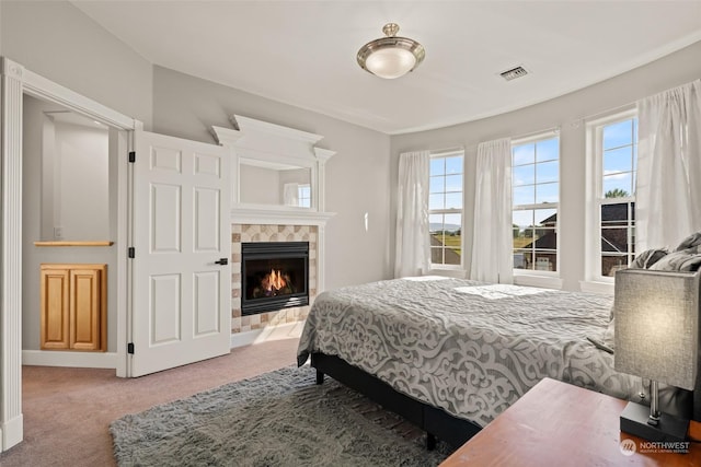 bedroom with a tiled fireplace and carpet flooring