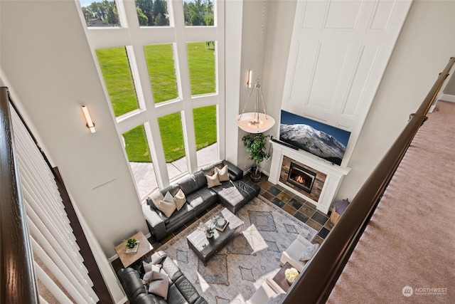 carpeted living room with a tiled fireplace and a towering ceiling