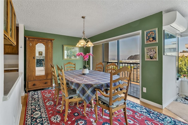 dining room with an inviting chandelier, a wall mounted air conditioner, plenty of natural light, and a textured ceiling