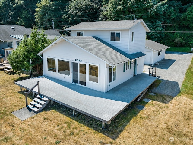 back of property with roof with shingles, a lawn, and a deck
