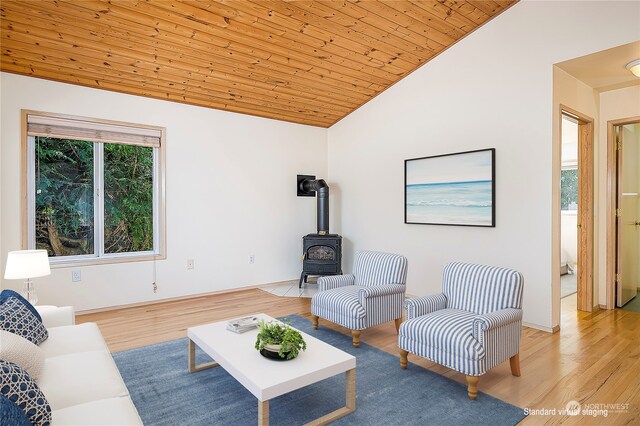 living room with wood ceiling, high vaulted ceiling, light hardwood / wood-style floors, and a wood stove