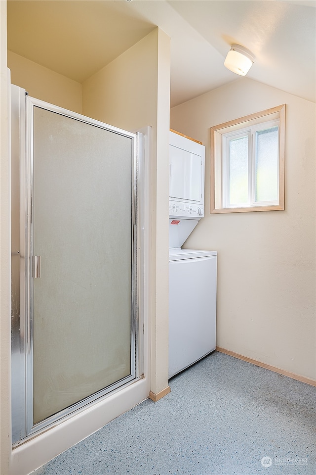 bathroom featuring an enclosed shower, stacked washer / drying machine, and vaulted ceiling