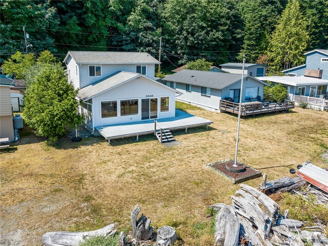 rear view of property featuring an outdoor structure, a deck, and a lawn