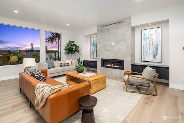 living room with light wood-type flooring and a tile fireplace