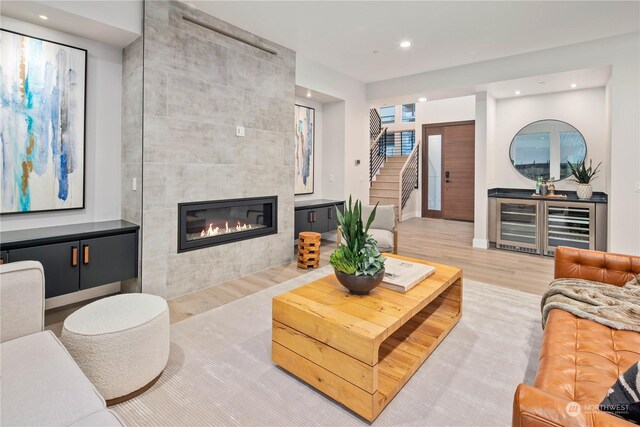 living room featuring light wood-type flooring, a fireplace, and beverage cooler