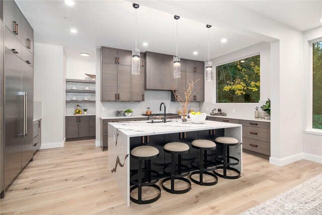 kitchen with light hardwood / wood-style flooring, a center island with sink, and a healthy amount of sunlight