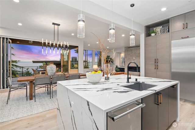 kitchen with sink, light hardwood / wood-style flooring, stainless steel appliances, and hanging light fixtures