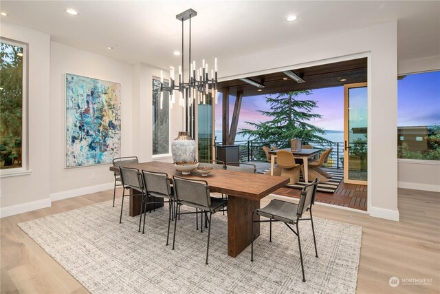 dining room featuring a notable chandelier, a water view, and light hardwood / wood-style flooring