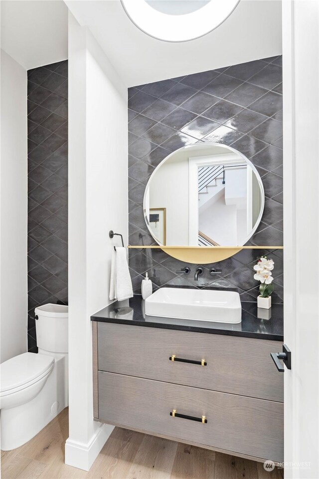 bathroom featuring vanity, tile walls, toilet, and hardwood / wood-style floors