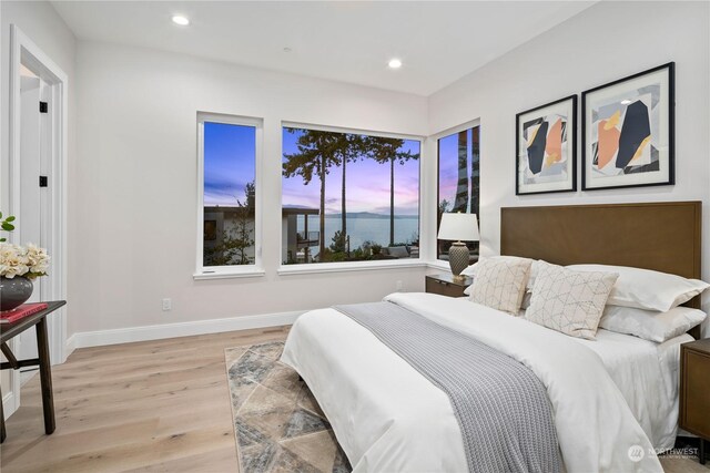 bedroom with light wood-type flooring and a water view