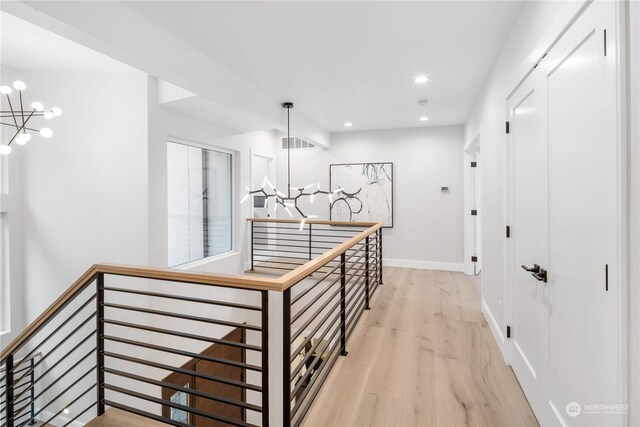 hall featuring light wood-type flooring and an inviting chandelier