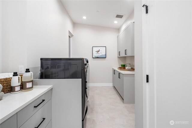 interior space featuring independent washer and dryer, light tile patterned flooring, and cabinets