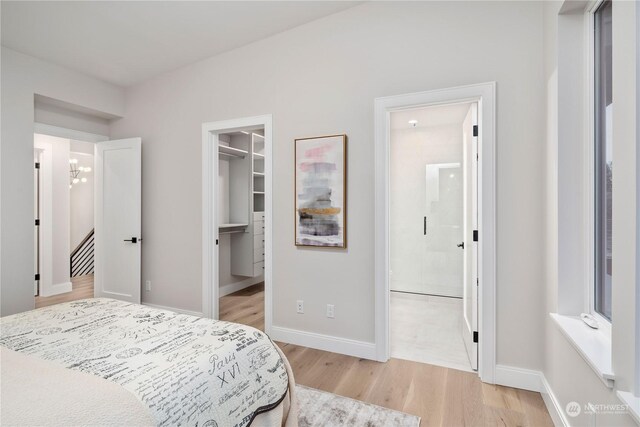 bedroom with ensuite bath, light wood-type flooring, a spacious closet, and a closet