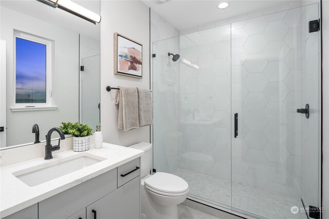 bathroom featuring toilet, vanity, and a shower with shower door