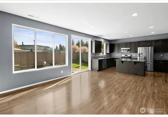 kitchen with dark brown cabinets, stainless steel appliances, wood-type flooring, and a center island