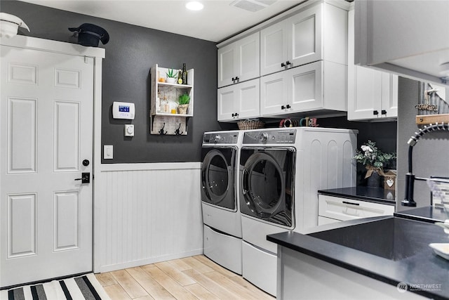 washroom with cabinet space, light wood finished floors, visible vents, wainscoting, and washer and dryer