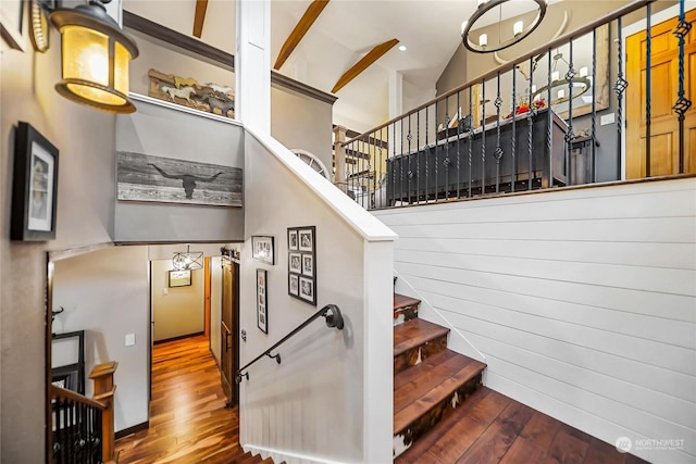 staircase with lofted ceiling, wood finished floors, and a notable chandelier