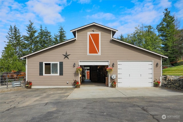 view of front facade featuring a barn, a garage, fence, and an outdoor structure