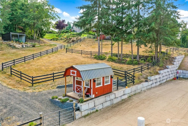 view of home's community with fence, an outbuilding, and a rural view