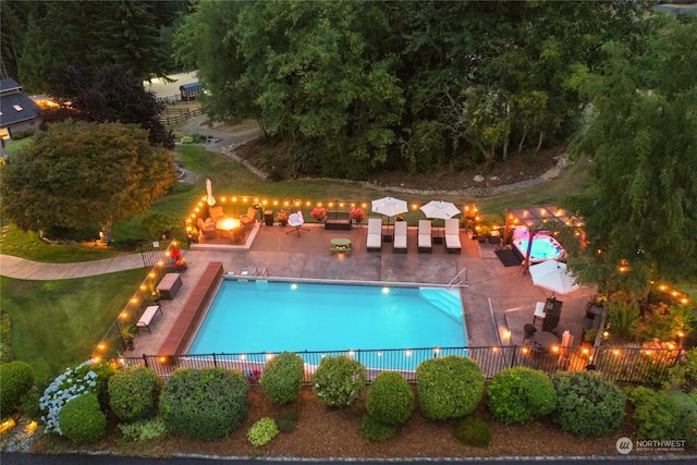 community pool with a patio, a yard, and fence