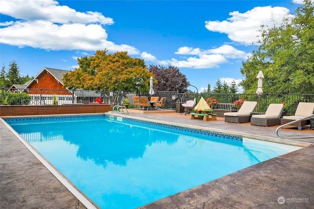 view of swimming pool featuring a patio area, fence, and a fenced in pool