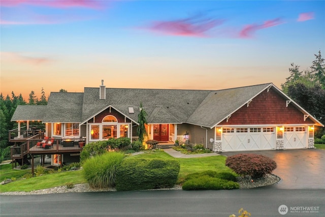 craftsman-style home with an attached garage, aphalt driveway, a chimney, and a front lawn