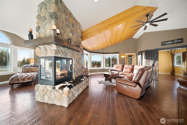 living area featuring high vaulted ceiling, a stone fireplace, hardwood / wood-style floors, and baseboards