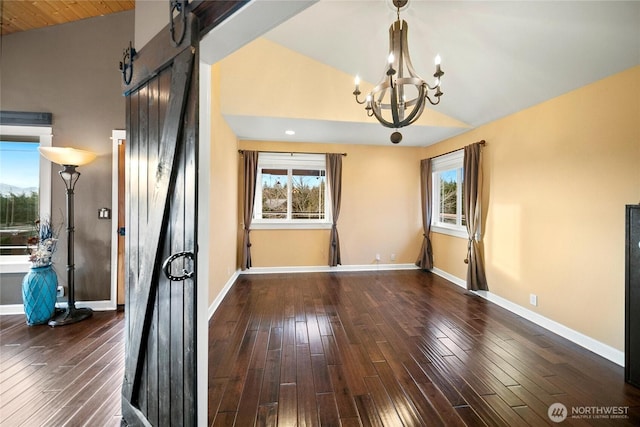 spare room with lofted ceiling, plenty of natural light, a barn door, and wood finished floors