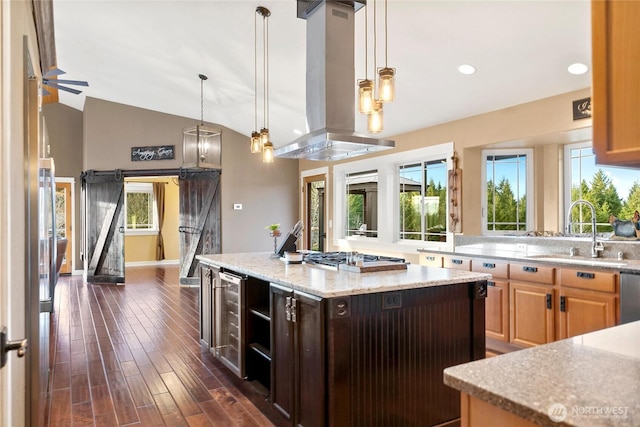 kitchen with a barn door, a center island, island exhaust hood, stainless steel appliances, and a sink