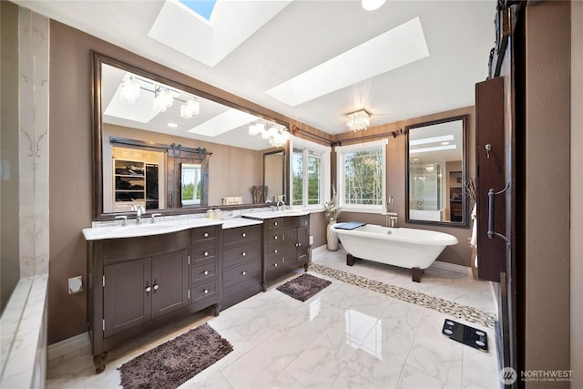 full bath featuring a skylight, marble finish floor, baseboards, and double vanity