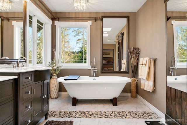 full bathroom featuring a freestanding bath, marble finish floor, plenty of natural light, and baseboards