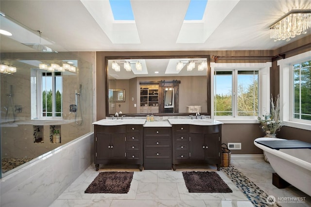 bathroom with marble finish floor, a skylight, visible vents, and a sink