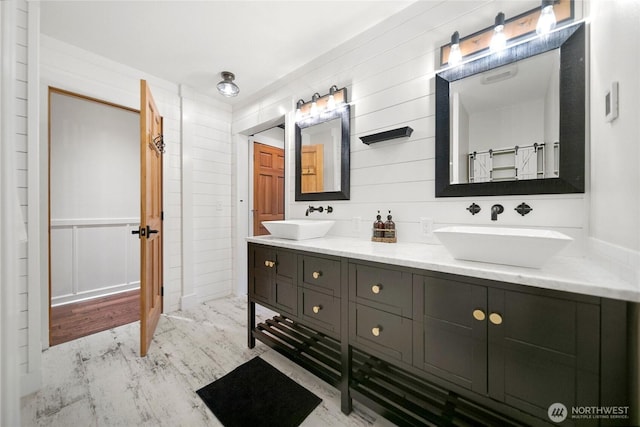 bathroom with wood finished floors, a sink, and double vanity