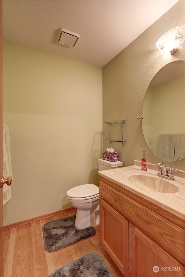 bathroom with vanity, toilet, and hardwood / wood-style floors