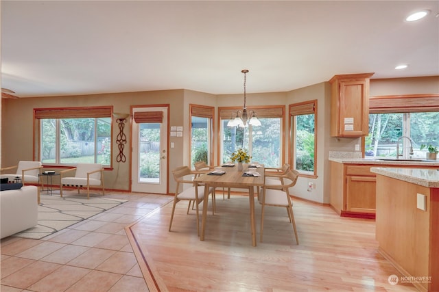 dining area featuring an inviting chandelier, light hardwood / wood-style flooring, sink, and a wealth of natural light