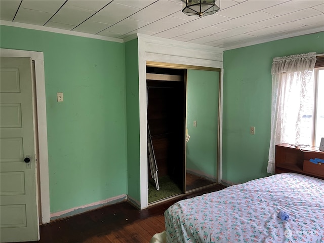 bedroom featuring wood-type flooring, crown molding, and a closet