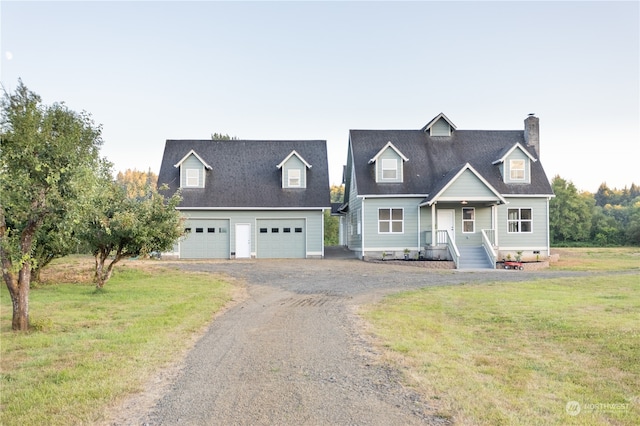 cape cod home featuring a garage and a front lawn