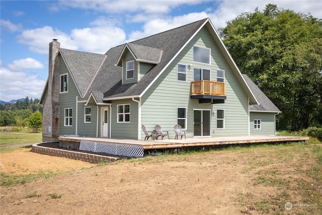 back of house featuring a balcony and a wooden deck