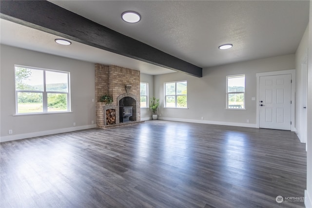 unfurnished living room with beamed ceiling, a brick fireplace, dark hardwood / wood-style floors, and brick wall