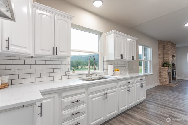 kitchen featuring light hardwood / wood-style floors, sink, brick wall, and white cabinets