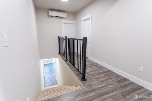 stairway with an AC wall unit and hardwood / wood-style floors