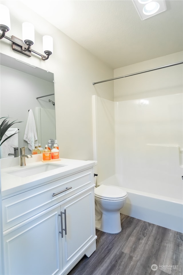 full bathroom with wood-type flooring, toilet, shower / bathtub combination, and vanity