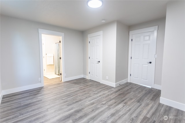 unfurnished bedroom featuring wood-type flooring and ensuite bathroom