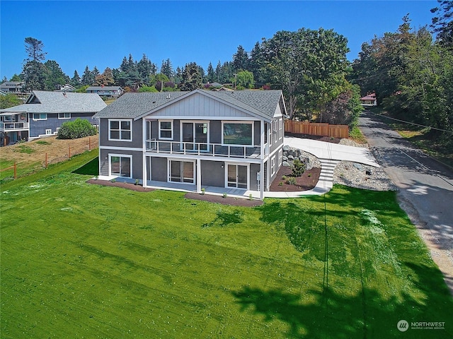 rear view of property featuring a yard, fence, and a sunroom